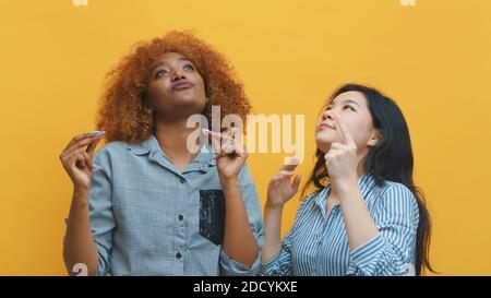 Deux jeunes femmes folles dansant. Isolées sur fond jaune. Photo de haute qualité Banque D'Images