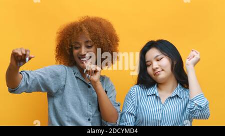 Deux jeunes femmes folles dansant. Isolées sur fond jaune. Photo de haute qualité Banque D'Images