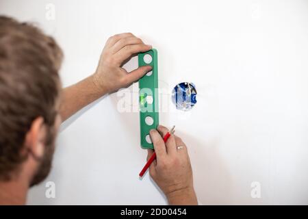 l'employé marque le trou dans le mur de la prise. Réparation et installation électrique. Copier l'espace. Banque D'Images