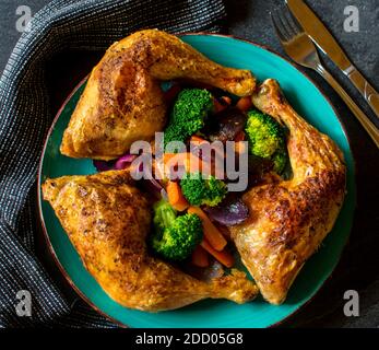 des cuisses de poulet rôties avec des légumes sur une assiette par le dessus Banque D'Images
