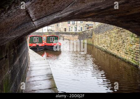 Bateaux étroits peints en rouge et blanc sous un pont de canal sur le canal Leeds et Liverpool à Skipton, dans le North Yorkshire UK Banque D'Images