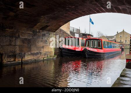 Bateaux étroits peints en rouge et blanc sous un pont de canal sur le canal Leeds et Liverpool à Skipton, dans le North Yorkshire UK Banque D'Images