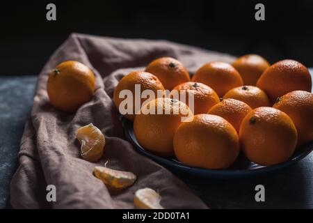 Pile de mandarine orange mûre ronde non pelée dans une assiette. Banque D'Images