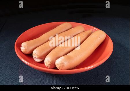 Les hot dogs sur la table en plaque rouge sur fond noir. Les produits de l'alimentation de la viande. Banque D'Images