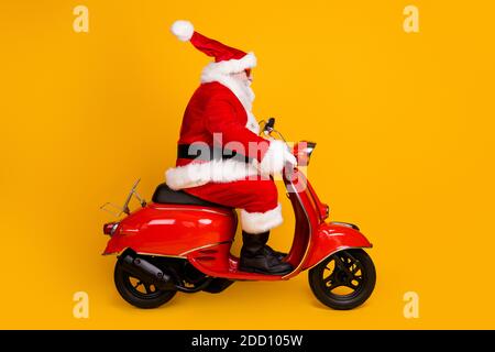 Profil vue de côté de son il gentil gras drôle épais Père Noël à poil blanc, vélo à moteur, vitesse rapide, dépêchez-vous shopping vente chapeau boule voler isolé Banque D'Images