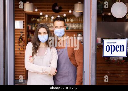 Prise de vue de jeunes serveuses et serveurs portant un masque facial pour la prévention tout en se tenant à la porte du restaurant après la réouverture de la pandémie du coronavirus. Banque D'Images