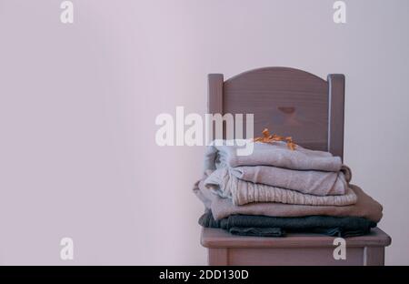 Panoramique hiver vêtements chauds dans une chaise violette avec une feuille sèche sur le dessus. Décembre 2020 concept. Banque D'Images