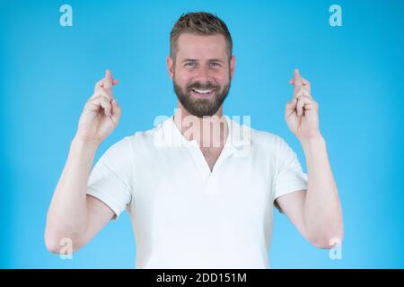 Jeune homme faisant un souhait isolé sur fond bleu Banque D'Images