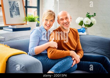 Photo d'un couple heureux assis sur un canapé à la maison et se liant les uns aux autres tout en se relaxant à la maison. Banque D'Images