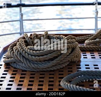 Corde de chanvre maritime forte enroulée sur un pont en teck poli. Banque D'Images