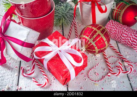 Composition festive avec branches de sapin, décoration de Noël et boules, boîte cadeau avec rubans festifs, bonbons de Noël et mugs pour chocolat chaud, blanc Banque D'Images