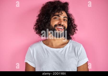 agréable indien arabe mâle dans la chemise regardant l'appareil photo, a le regard amical, ouvert-esprit gars isolé sur fond rose Banque D'Images