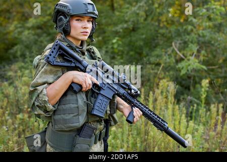 portrait d'une femme militaire confiante avec un fusil en forêt, chasseur femelle en costume de camouflage avec un fusil stand dans la nature seule Banque D'Images