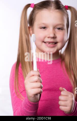 Jeune fille d'âge préscolaire avec les premiers incisives adultes et une brosse à dents. La dent de lait est tombée, et une dent permanente pousse dans la bouche ouverte. Dentaire Banque D'Images