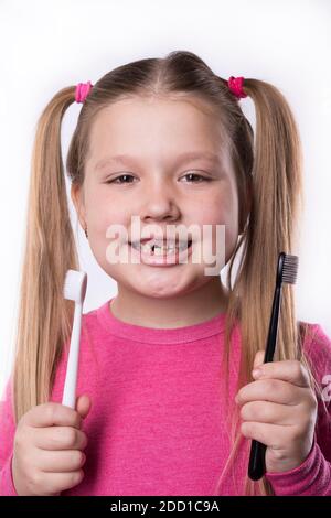 Jeune fille d'âge préscolaire avec les premiers incisives adultes et une brosse à dents. La dent de lait est tombée, et une dent permanente pousse dans la bouche ouverte. Dentaire Banque D'Images