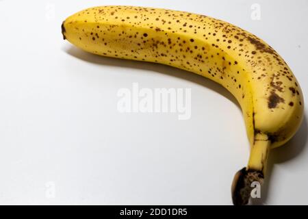 La banane surmûre avec des points noirs sur fond blanc montre une alimentation saine pour les végétariens et les végétaliens avec des taches sombres comme l'ingrédient de prise de vue en studio conta Banque D'Images