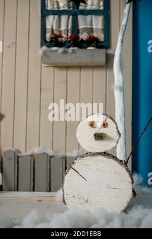 Studio décoratif de Noël avec une maison avec porte bleue, banc en bois et skis, bonhomme de neige, faux nuages et neige Banque D'Images