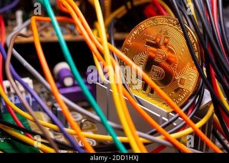 Cryptocurrency virtuelle Bitcoin argent médaille d'or sur un ordinateur de circuits imprimés PCB entouré par différents câbles colorés. L'avenir de l'argent. Banque D'Images