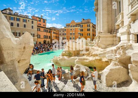 Une vue latérale sur la fontaine de Trevi de la Piazza di Trevi tandis que les touristes profitent d'une journée ensoleillée dans le centre de Rome. Banque D'Images