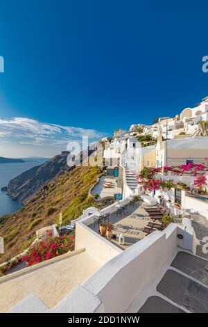 Ville d'Oia sur l'île de Santorin, Grèce. Maisons bleues blanches traditionnelles célèbres avec des fleurs sous un temps ensoleillé caldeira, mer Égée. Belle vue d'été Banque D'Images