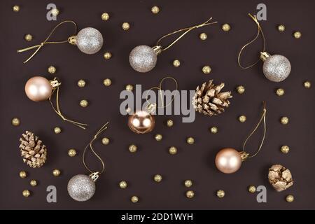 Elégant plat de Noël avec boules décoratives en or et en argent, cônes de sapin peints et petits boules de neige dorées sur fond noir foncé Banque D'Images