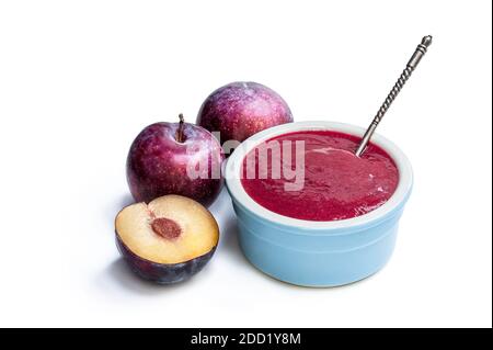 Chutney maison de prunes dans un bol d'argile isolé sur blanc Banque D'Images