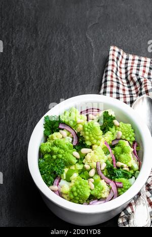 Chou-fleur romanesco avec câpres et salade d'oignons sur pierre noire arrière-plan Banque D'Images