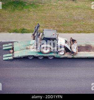 Une pelle hydraulique tire dans une remorque de camion pour le transport vers autre emplacement Banque D'Images