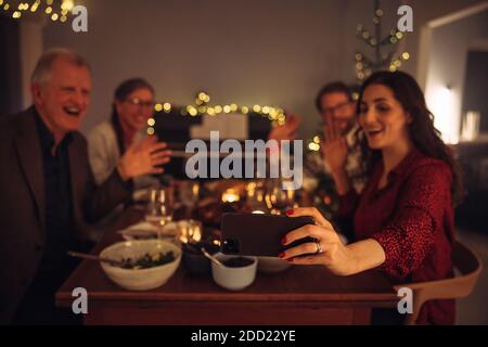 La famille se connecte avec ses proches lors d'un appel vidéo pendant le dîner de la veille de Noël. Célébration de noël en ligne à la maison pendant la pandémie. Banque D'Images
