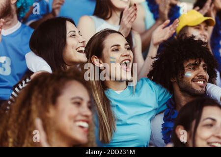 Les fans argentins de football regardant le match au stade. Groupe de supporters de l'équipe de football Argentine regardant le match et applaudisant des stands dans t Banque D'Images