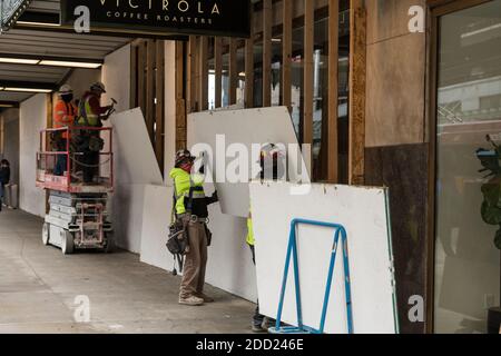 Seattle, États-Unis. 23 novembre 2020. Des employés de milieu de journée qui descendent des planches couvrant les fenêtres de Victrola Coffee dans le bâtiment Amazone. Banque D'Images