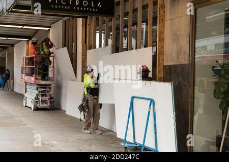 Seattle, États-Unis. 23 novembre 2020. Des employés de milieu de journée qui descendent des planches couvrant les fenêtres de Victrola Coffee dans le bâtiment Amazone. Banque D'Images