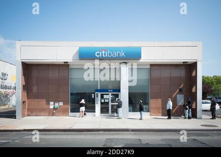 Les clients maintiennent une distance sociale et attendent patiemment d'entrer dans une banque sur Northern Boulevard, dans Queens Banque D'Images