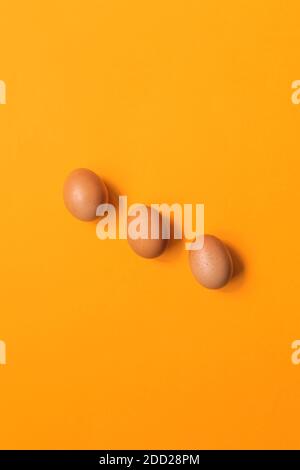 trois œufs minimalistes sur fond orange Banque D'Images