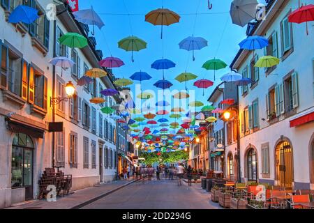 Scène nocturne à Carouge, Genève, Suisse le long de la rue Saint Joseph recouverte de parasols colorés. Banque D'Images