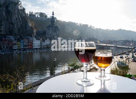 Boire de la bière d'abbaye belge sombre et forte avec des fromages par temps ensoleillé avec belle vue sur la rivière Maas et la ville de Dinant, Belgique Banque D'Images