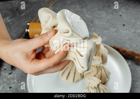 la main tient le chikali par la queue. Khinkali dans un restaurant géorgien à la main. Cuisine géorgienne Banque D'Images