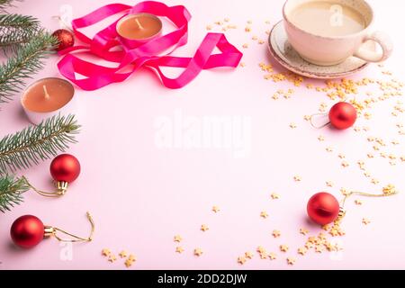 Composition cadre Noël ou nouvel an. Décorations, boules rouges, branches de sapin et d'épicéa, tasse de café, bougies sur fond de papier rose. Vue latérale Banque D'Images