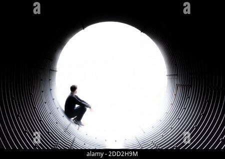 Silhouette d'un homme regardant pensivement au bord d'un tunnel à travers un vide blanc. Espace pour placer le texte. Concept Banque D'Images