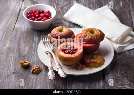 Pommes cuites farcies de canneberges, de noix et de miel à la cannelle sur une plaque blanche sur une table en bois, concentration sélective. Délicieux légumes sains d Banque D'Images