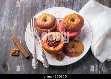 Pommes cuites farcies de canneberges, de noix et de miel à la cannelle sur une plaque blanche sur une table en bois, concentration sélective. Délicieux légumes sains d Banque D'Images