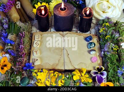 Livre ouvert avec des pages vides, des bougies noires, des cristaux de reiki et des herbes sur table de sorcière. Concept ésotérique, occulte et mystique, médecine alternative backgrou Banque D'Images