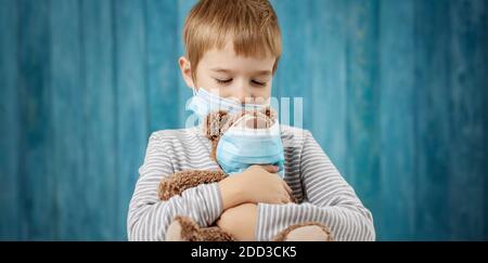 Petit garçon avec un ours en peluche dans des masques médicaux pour le visage Banque D'Images