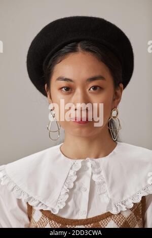 Portrait de la jeune femme asiatique dans un élégant chapeau regardant appareil photo Banque D'Images