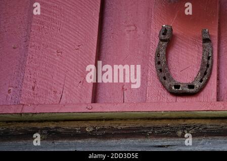 Vieille chaussure de cheval rouillée sur un mur de grange rouge pour Bonne chance. Photo de haute qualité Banque D'Images