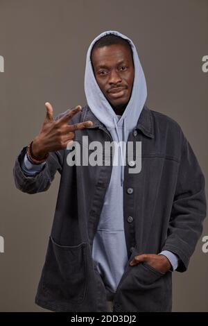 Portrait du jeune homme africain en vêtements élégants posant à caméra isolée sur fond gris Banque D'Images