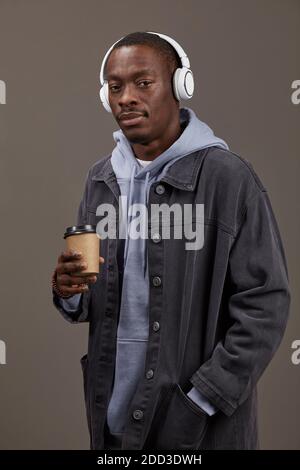 Portrait de l'homme africain dans des vêtements élégants tenant une tasse de café et musique Banque D'Images