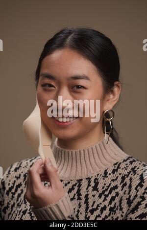 Portrait d'une femme asiatique souriant à l'appareil photo tout en portant une protection masque sur fond gris Banque D'Images