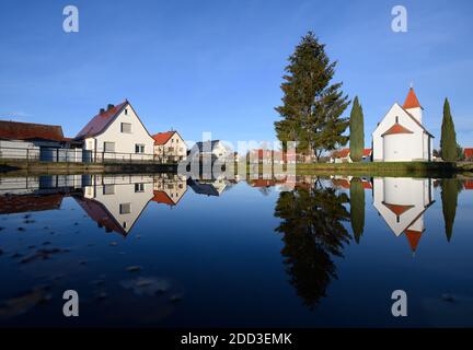 Saalau, Allemagne. 24 novembre 2020. La chapelle de la place du village à Saalau, les arbres et les maisons se reflètent dans un étang. Le village du nord du district de Bautzen en Saxe orientale appartient à la ville de Wittichenau depuis 1994. Il est situé dans le paysage de la lande et de l'étang du Haut-Lusatien et fait partie de la région sorabe. Credit: Robert Michael/dpa-Zentralbild/ZB/dpa/Alay Live News Banque D'Images