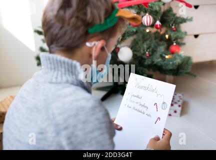 L'enfant écrit la liste de souhaits de Noël pendant la crise corona en isolement Banque D'Images